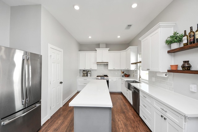 kitchen featuring visible vents, a center island, stainless steel appliances, open shelves, and a sink