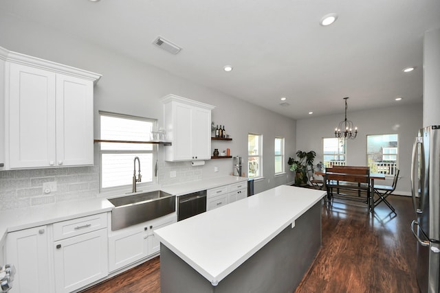 kitchen featuring a center island, visible vents, freestanding refrigerator, a sink, and dishwashing machine