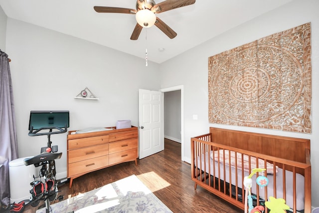 bedroom with a nursery area, ceiling fan, wood finished floors, and baseboards