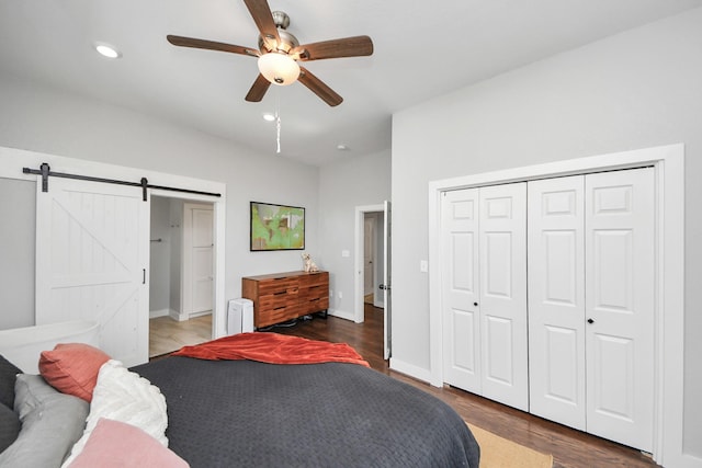 bedroom with a barn door, baseboards, wood finished floors, a closet, and recessed lighting