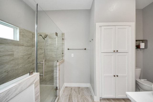 bathroom with baseboards, a shower stall, and toilet