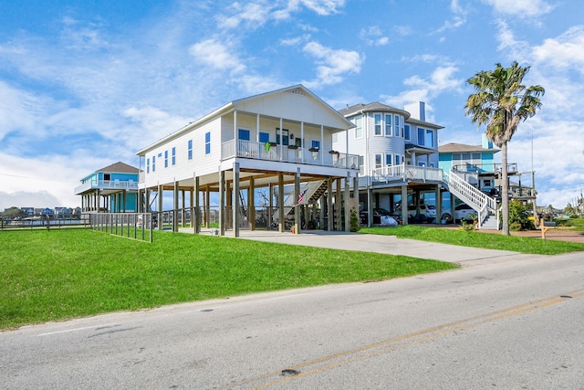 view of front of home featuring a porch, concrete driveway, a front yard, a carport, and stairs