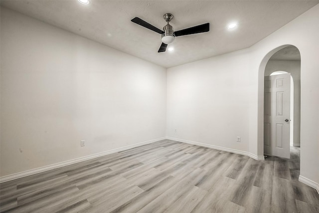 unfurnished room featuring baseboards, arched walkways, a ceiling fan, wood finished floors, and recessed lighting