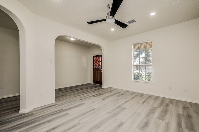 spare room featuring baseboards, arched walkways, a ceiling fan, wood finished floors, and recessed lighting