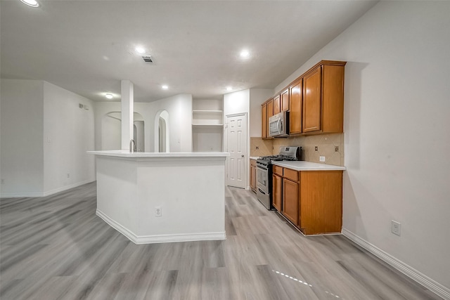 kitchen featuring brown cabinetry, tasteful backsplash, visible vents, and stainless steel appliances