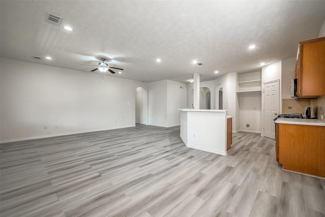 kitchen with arched walkways, open floor plan, visible vents, and brown cabinets