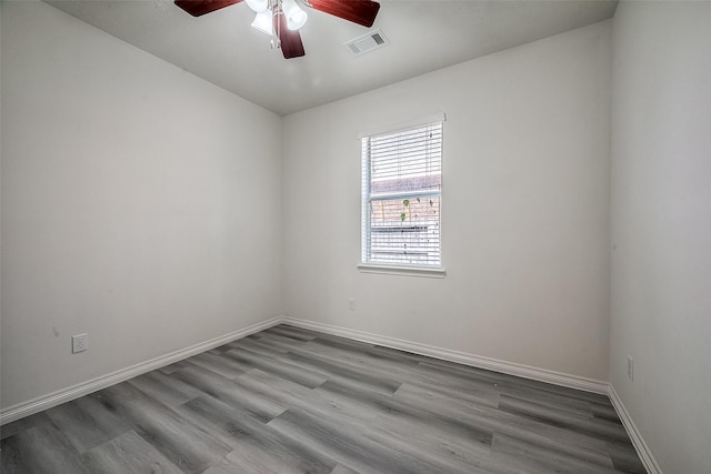 empty room with ceiling fan, wood finished floors, visible vents, and baseboards