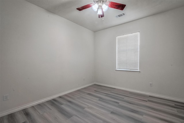 unfurnished room with a ceiling fan, baseboards, visible vents, and wood finished floors