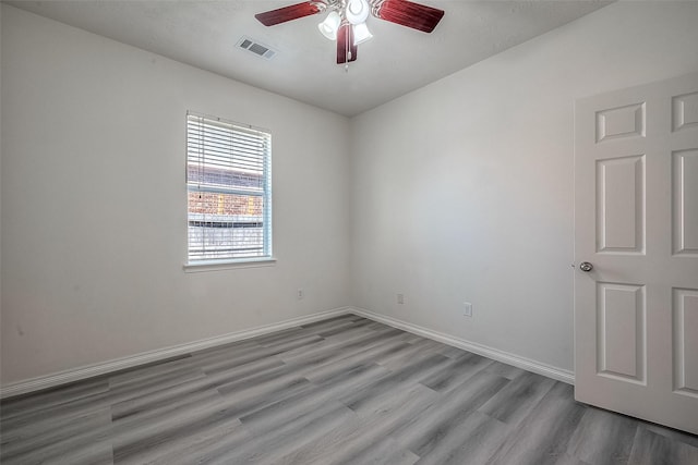 empty room with a ceiling fan, visible vents, baseboards, and wood finished floors