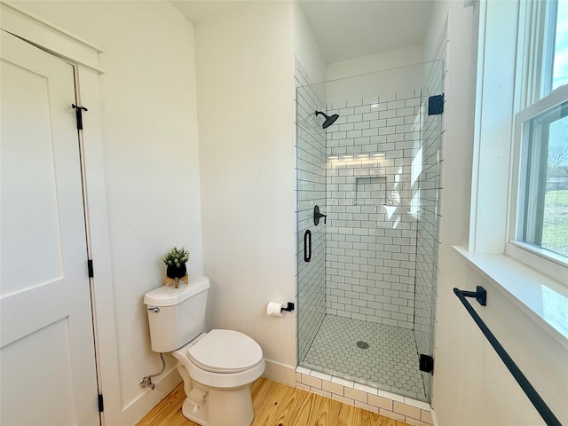 full bath with toilet, a shower stall, baseboards, and wood finished floors