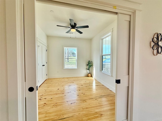 interior space with a ceiling fan, baseboards, and wood finished floors