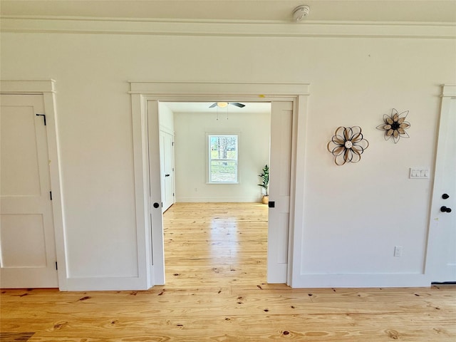 corridor with light wood-type flooring and baseboards