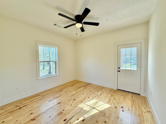 unfurnished room featuring wood-type flooring, visible vents, and baseboards