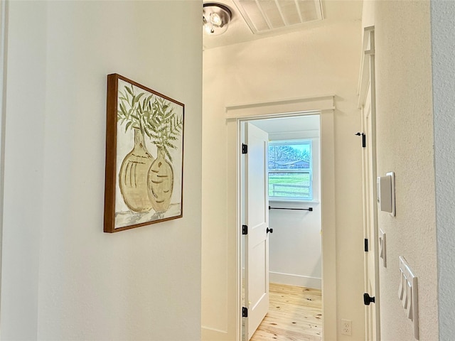 hall with baseboards, visible vents, and wood finished floors