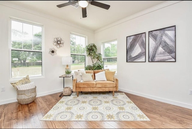 sitting room featuring ornamental molding, baseboards, and wood finished floors