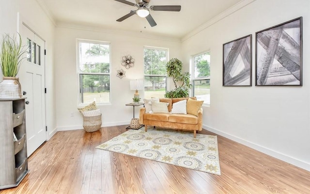 sitting room featuring baseboards, ornamental molding, and light wood-style floors