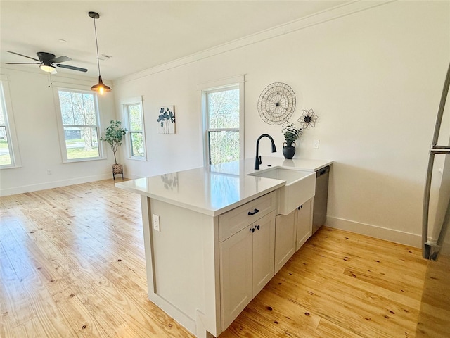 kitchen featuring a sink, light countertops, dishwasher, light wood finished floors, and crown molding