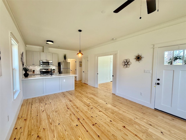 kitchen featuring stainless steel appliances, crown molding, a peninsula, and decorative backsplash