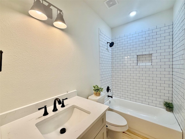 bathroom featuring a textured wall, toilet, shower / bath combination, vanity, and visible vents