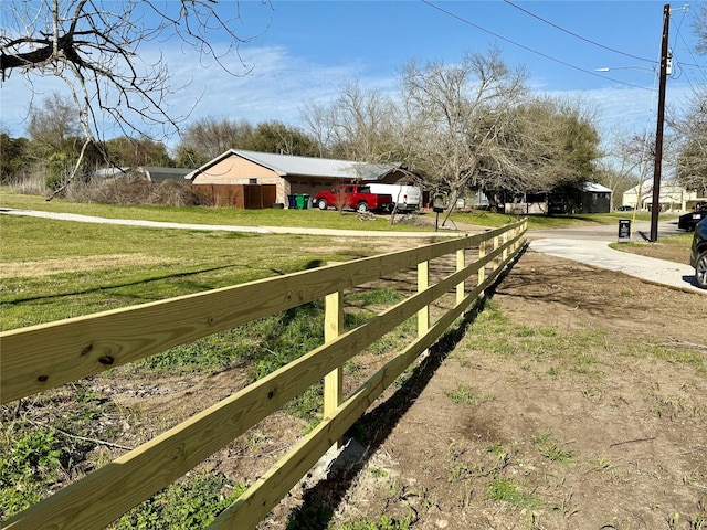 view of yard with dirt driveway and fence