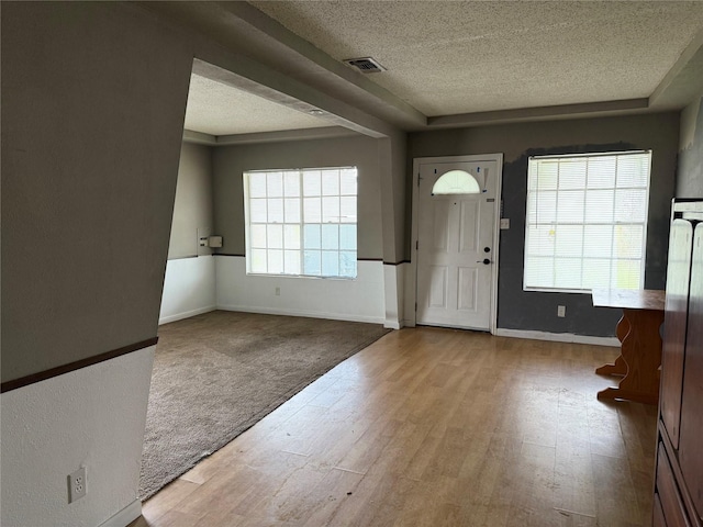 entryway featuring visible vents, a textured ceiling, baseboards, and wood finished floors