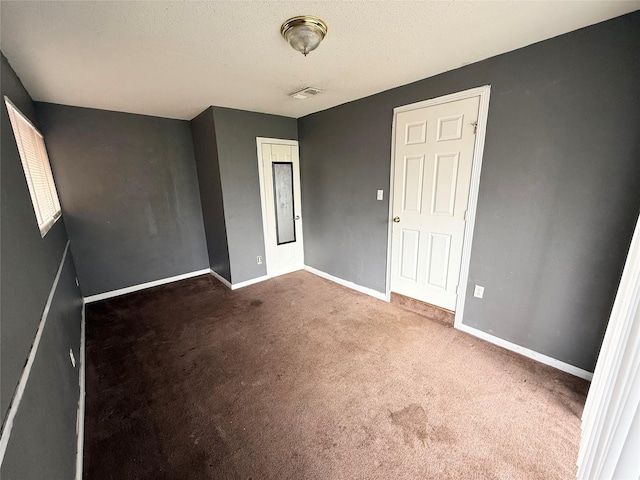 unfurnished bedroom featuring carpet, visible vents, a textured ceiling, and baseboards