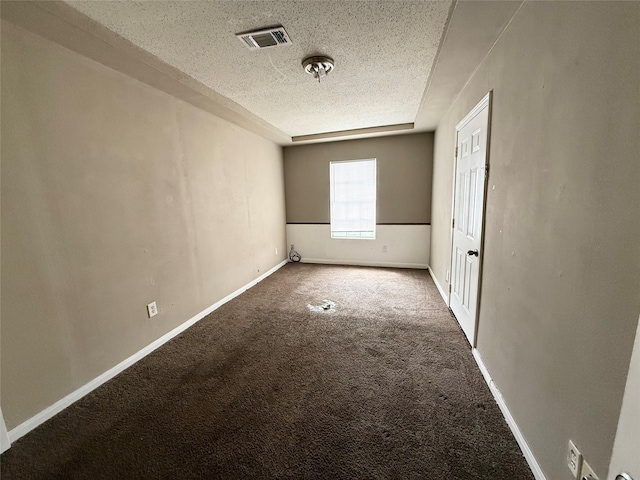 empty room featuring a textured ceiling, carpet floors, visible vents, and baseboards