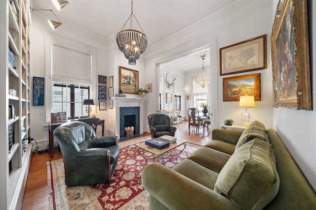 living room with a healthy amount of sunlight, ornamental molding, a fireplace with raised hearth, and wood finished floors