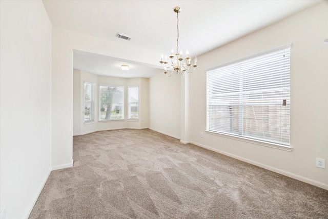 carpeted empty room with a chandelier, visible vents, and baseboards