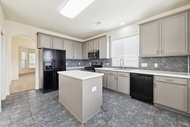 kitchen featuring arched walkways, gray cabinetry, a sink, and black appliances