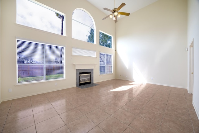 unfurnished living room with baseboards, a fireplace, a ceiling fan, and tile patterned floors