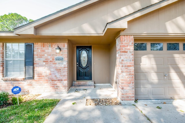 doorway to property with brick siding and an attached garage