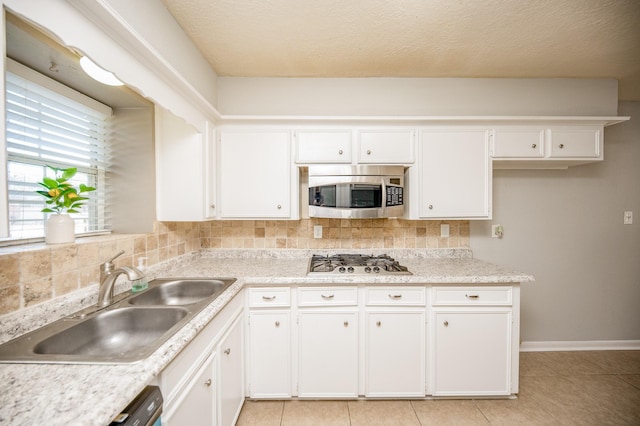 kitchen featuring a sink, white cabinets, light countertops, appliances with stainless steel finishes, and backsplash