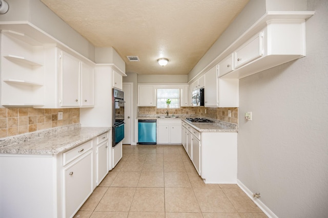 kitchen featuring light tile patterned floors, stainless steel appliances, visible vents, white cabinetry, and a sink