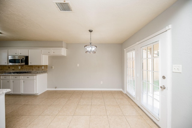 kitchen featuring light tile patterned flooring, visible vents, white cabinets, appliances with stainless steel finishes, and decorative backsplash