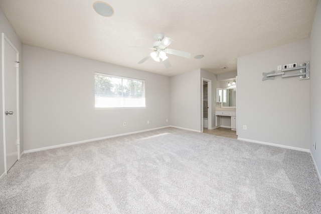 unfurnished bedroom with carpet floors, baseboards, a textured ceiling, and ensuite bathroom