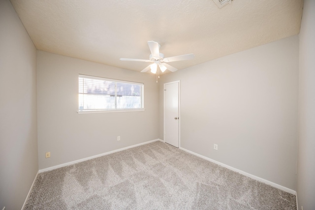 spare room featuring a ceiling fan, light carpet, and baseboards