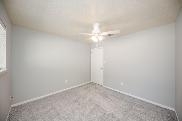 carpeted empty room featuring ceiling fan, a textured ceiling, and baseboards