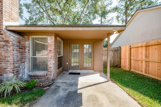 entrance to property with brick siding, fence, and french doors