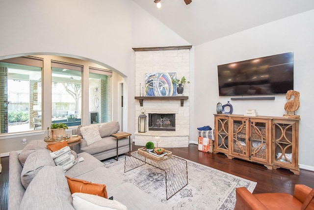 living room with baseboards, arched walkways, wood finished floors, a fireplace, and high vaulted ceiling