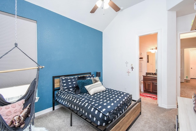 carpeted bedroom with baseboards, lofted ceiling, ceiling fan, ensuite bathroom, and a sink