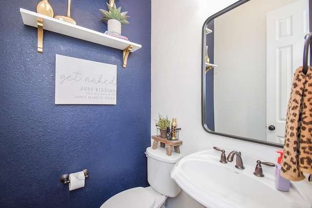 bathroom featuring a textured wall, a sink, and toilet