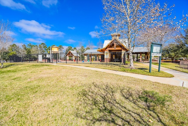 view of property's community with playground community, a lawn, and fence