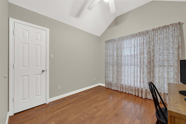 unfurnished office featuring a ceiling fan, baseboards, vaulted ceiling, and wood finished floors