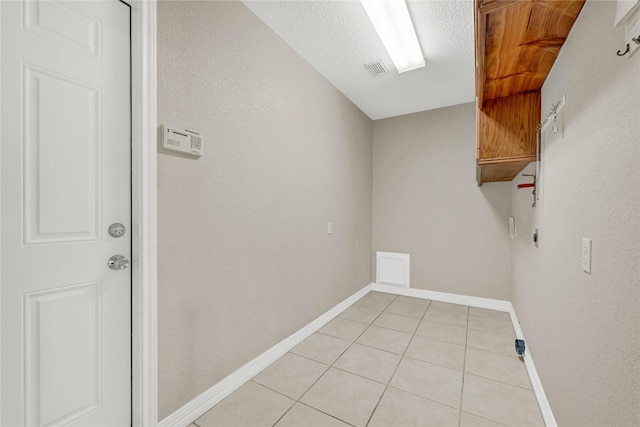 washroom featuring light tile patterned floors, a textured ceiling, visible vents, baseboards, and cabinet space