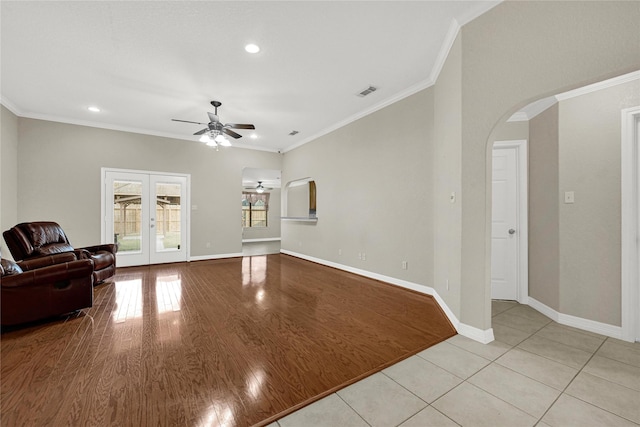 living area with arched walkways, ornamental molding, and french doors