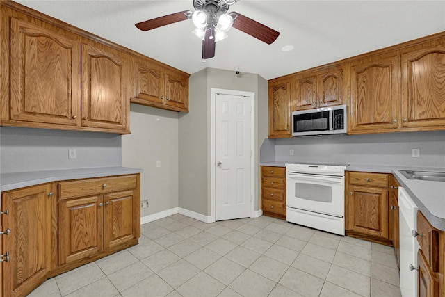 kitchen featuring white appliances, baseboards, brown cabinets, and light countertops