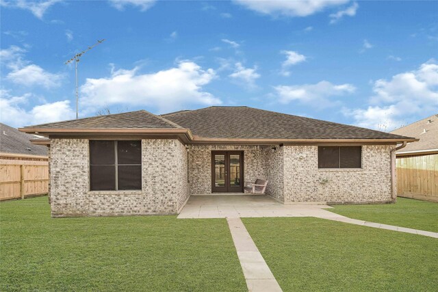 rear view of house with french doors, brick siding, a shingled roof, a lawn, and a fenced backyard