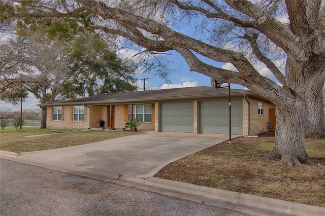 single story home with a front lawn, concrete driveway, brick siding, and an attached garage