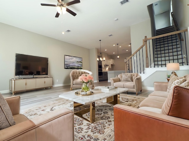 living area with visible vents, stairway, recessed lighting, ceiling fan with notable chandelier, and light wood-style floors